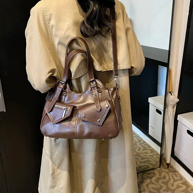 Épaule et bras d'une femme en trench beige supportant le sac brun aux reflets lustrés