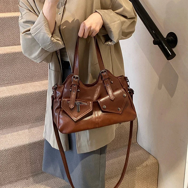 Dans un escalier, une silhouette vêtue de beige tient le sac marron par ses deux anses courtes