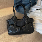 Sur un tapis clair, le sac noir repose devant un jean brut, anses dressées et flancs affaissés