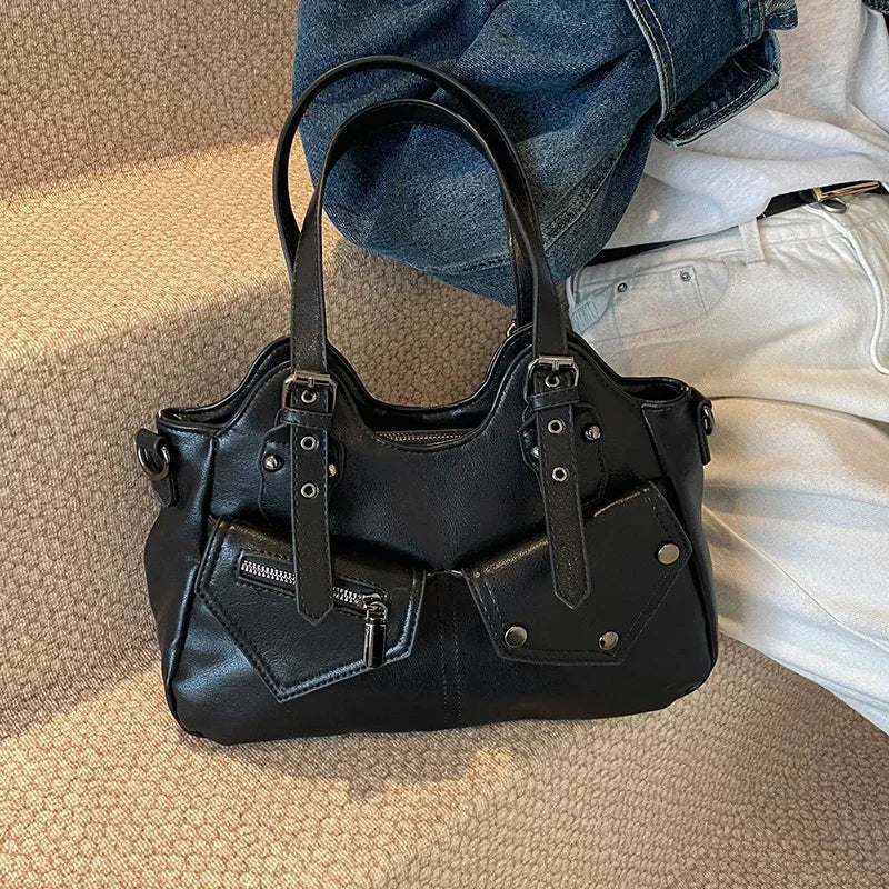 Sur un tapis clair, le sac noir repose devant un jean brut, anses dressées et flancs affaissés