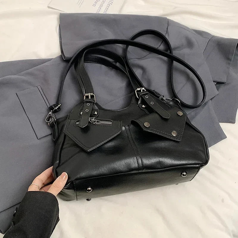 Corps noir souple soulevé d'un drap gris, patte à boucle et poche zippée en pointe bien visibles