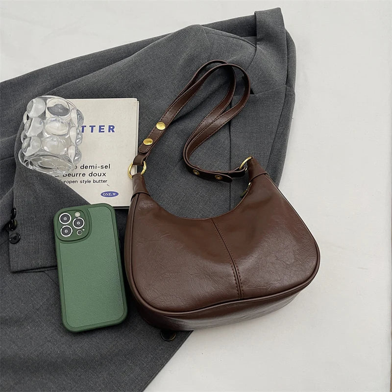 Posé à plat sur une veste grise, le sac brun café voisine un téléphone vert amande
