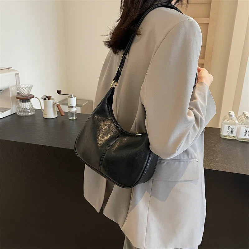 Sous le bras, sur un blazer beige clair, le hobo noir épouse la ligne de la hanche