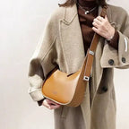 Portée en croisé sur un long manteau beige, la besace caramel se cale contre la hanche