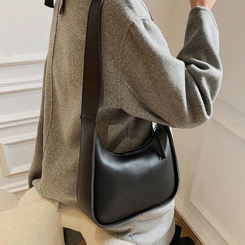 Épaule d'une veste grise portant la besace noire, volume compact posé contre la hanche