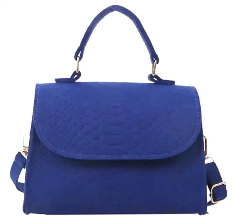 Bleu roi et grain reptile, ce sac rigide à rabat arrondi porte une anse haute et une sangle