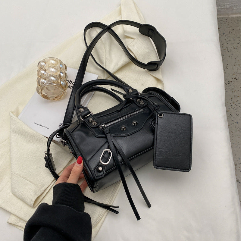 Posé sur un tissu écru, le sac noir déploie sa bandoulière large et ses longues lanières