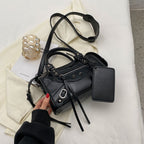 Posé sur un tissu écru, le sac noir déploie sa bandoulière large et ses longues lanières
