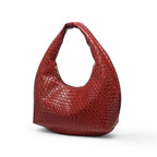 Rouge brique et tressé, le petit hobo pose de trois quarts, base élargie et anse ronde bien marquée