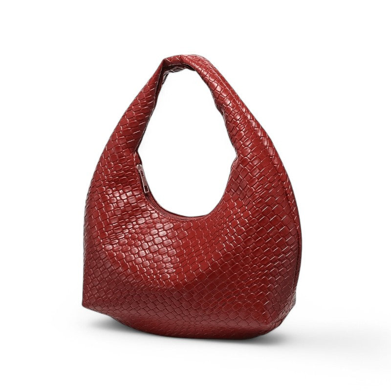 Rouge brique et tressé, le petit hobo pose de trois quarts, base élargie et anse ronde bien marquée