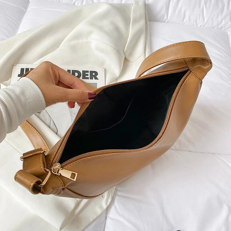 Ouvert à deux mains, l'intérieur noir du sac camel montre sa doublure lisse et sa poche plate