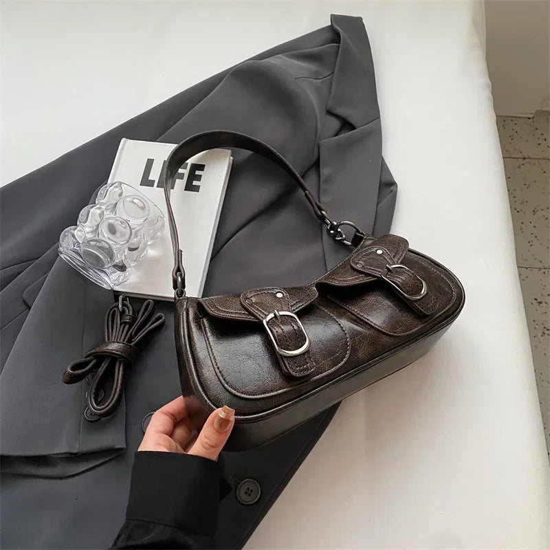 Posé sur un blazer gris, le sac baguette brun foncé dévoile ses surpiqûres et ses boucles