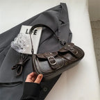 Posé sur un blazer gris, le sac baguette brun foncé dévoile ses surpiqûres et ses boucles