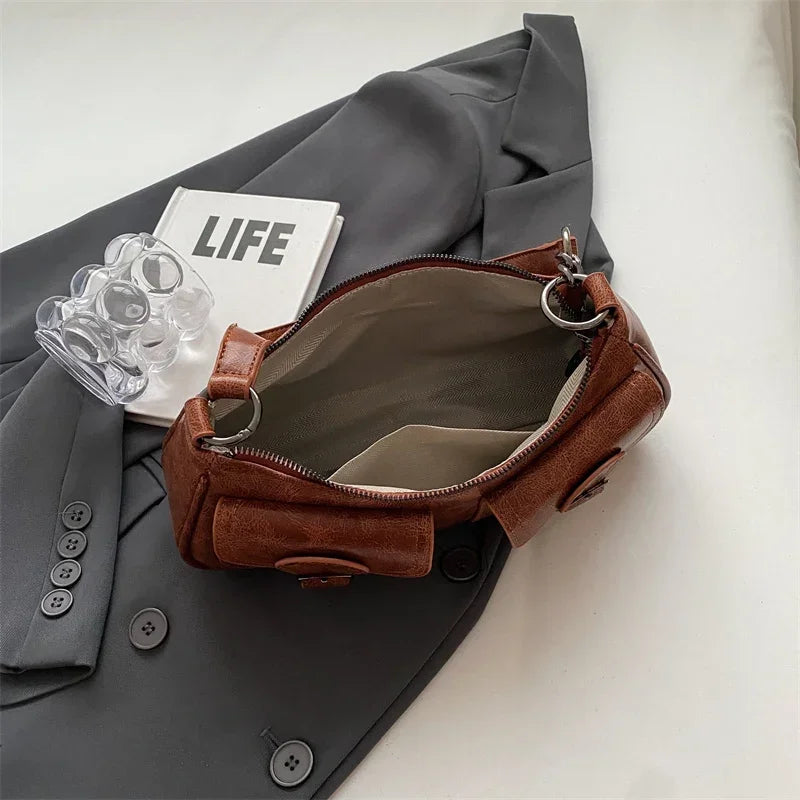 Intérieur du sac cognac ouvert sur une doublure claire, anse rabattue et zip apparent
