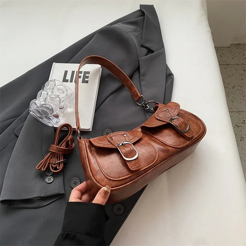 Version cognac tenue en main au-dessus d'un blazer gris, poche avant et boucle bien nettes