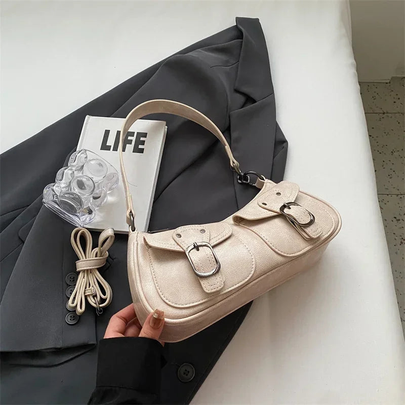 Beige écru sur un blazer gris, le sac baguette est tenu en main, rabats et boucle visibles