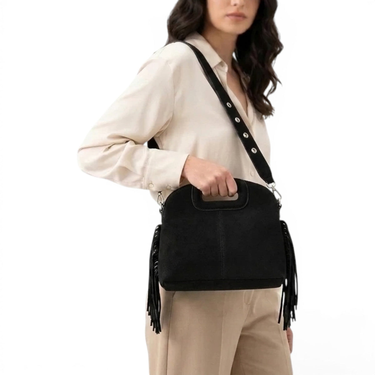 En croisé sur un chemisier crème, le sac noir laisse pendre ses longues franges souples