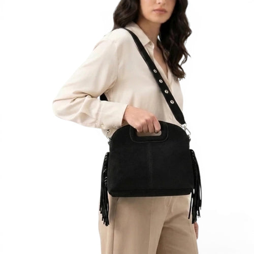 En croisé sur un chemisier crème, le sac noir laisse pendre ses longues franges souples