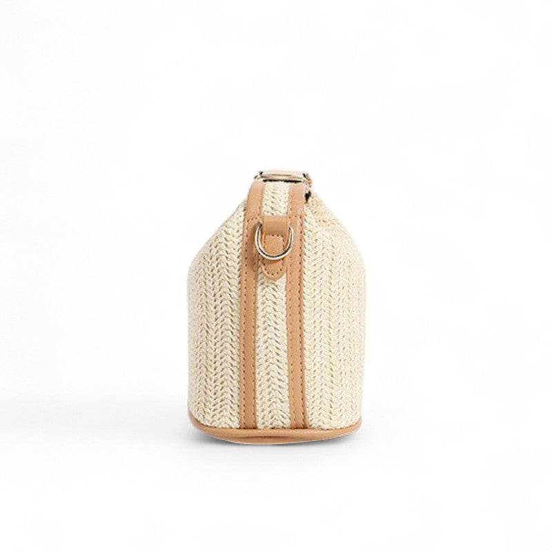 Étroit de dos, le sac en paille montre sa sangle verticale et son anneau métallique doré