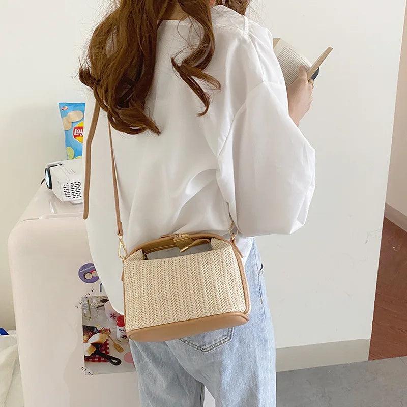 De dos, une jeune femme en chemise blanche porte le sac en paille en bandoulière sur un jean