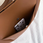 Poche intérieure du cabas marron fermée par un bouton aimanté, un téléphone y est glissé