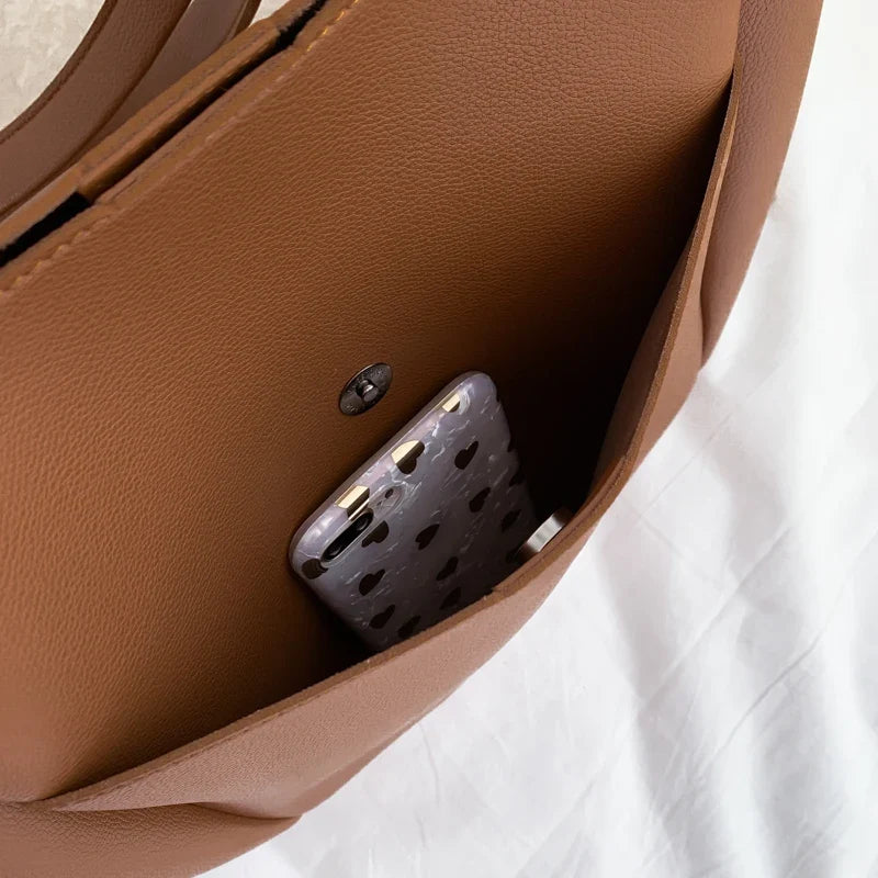 Poche intérieure du cabas marron fermée par un bouton aimanté, un téléphone y est glissé