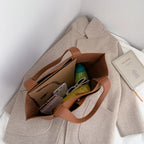 Ouvert sur son contenu, le cabas marron accueille trousse, gourde verte, lunettes et portefeuille