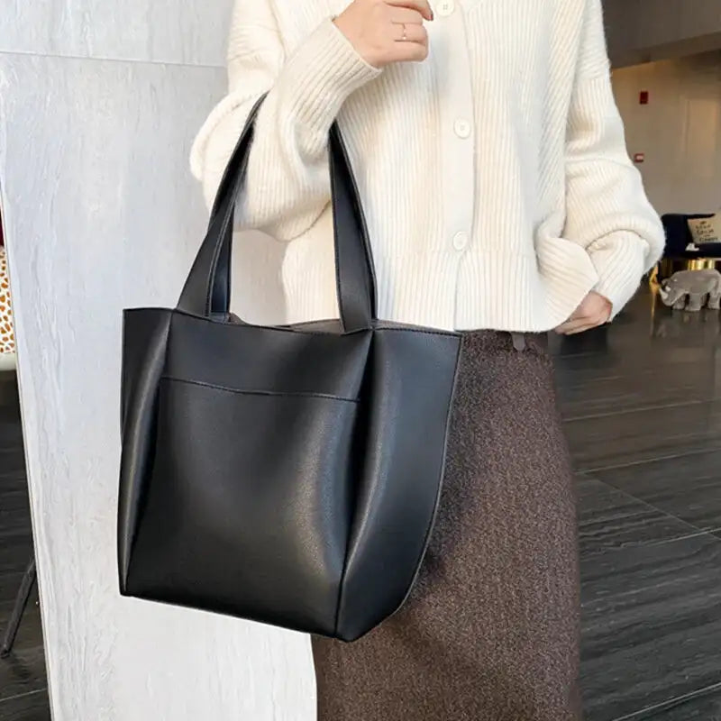 À l'épaule sur un cardigan blanc et une jupe marron, le tote noir tombe bien droit