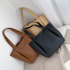 Trois coloris réunis, cabas marron, noir et beige posés sur un tissu clair, anses mêlées