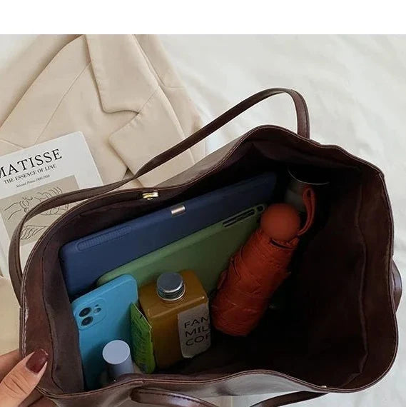 Dans le sac ouvert : tablette, téléphone, gourde et parapluie tiennent côte à côte au fond