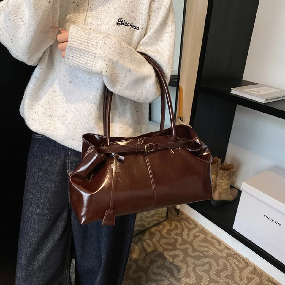 Contre un pull écru et un jean brut, le sac acajou repose au creux du coude, boucle en avant