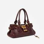 Cuir végan bordeaux, sac bowling de trois quarts, sangles latérales et cadenas doré massif