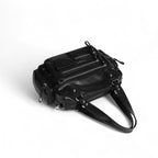 Même cadrage plongeant, resserré sur le sac noir posé sur le flanc et sa sangle enroulée