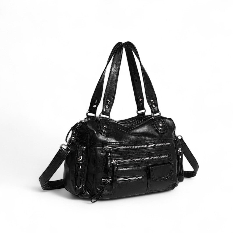 Trois quarts du sac noir souple, poches plaquées, glissières argentées et sangle réglable
